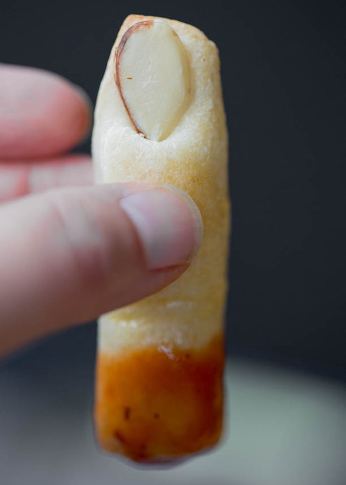 Witch finger will you eat first? Here are two ways to make delightfully creepy witches' fingers breadsticks - use either sliced almonds for the gnarly fingernail or go for bell pepper for a nut-free version. #halloweenfood #severedfingers #witchesfingersbreadsticks