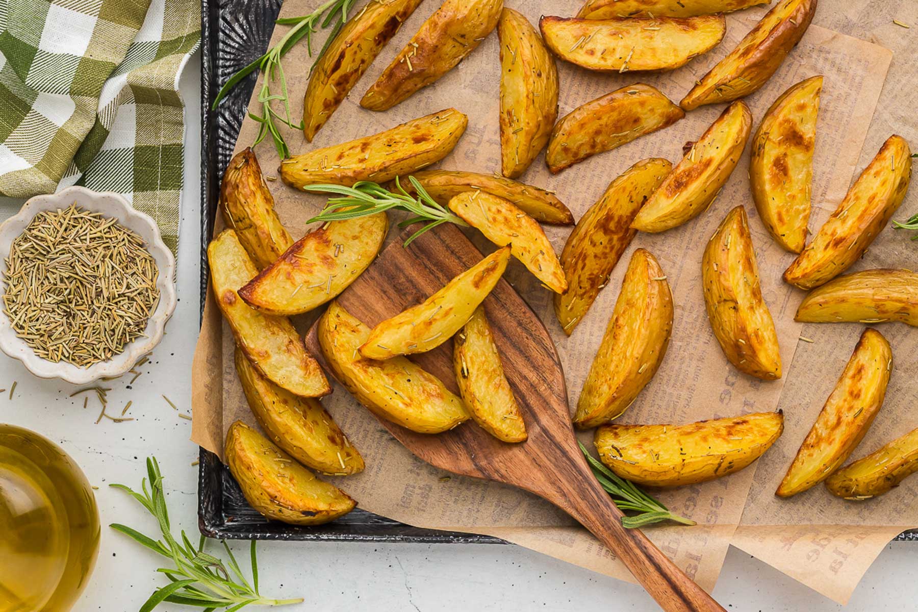Rosemary Roasted Potatoes on a baking sheet with a wooden spoon