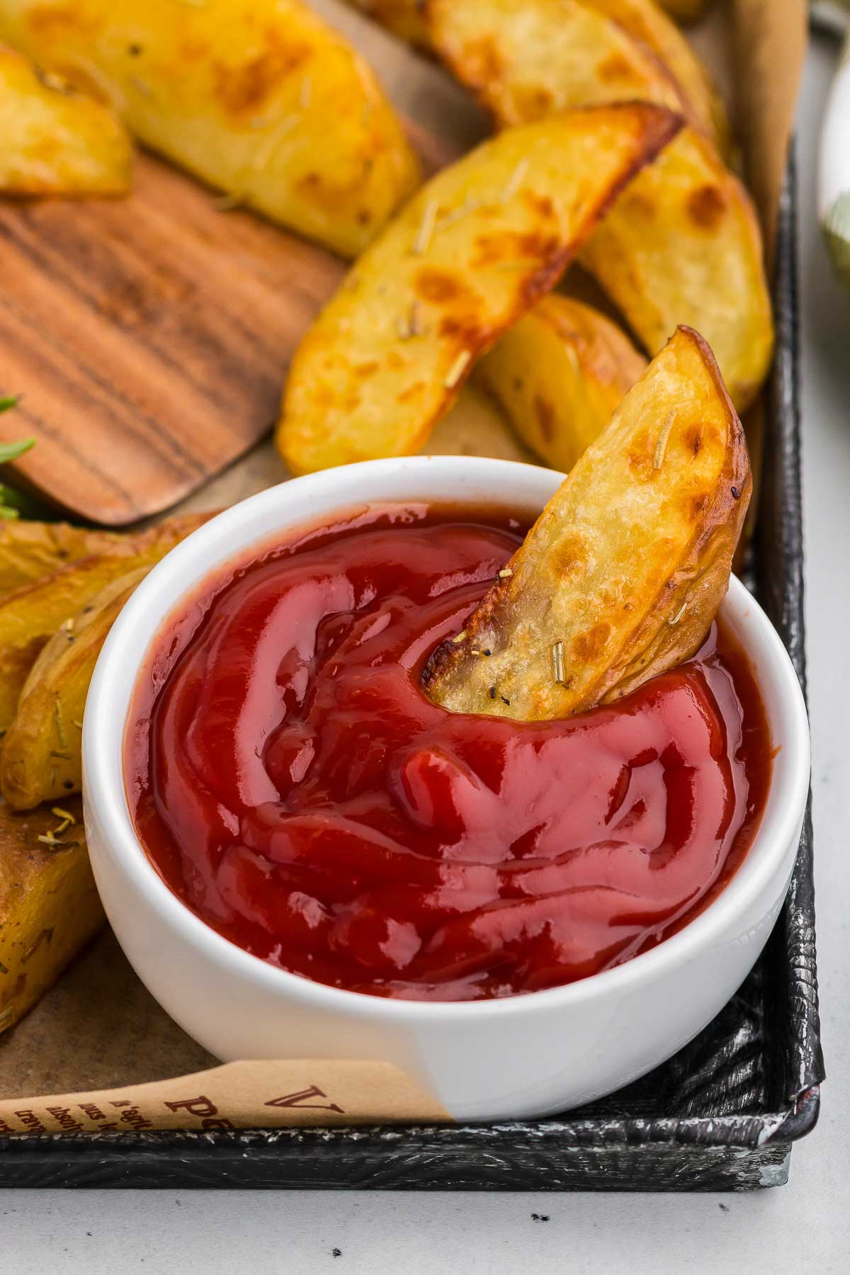 A cup of ketchup with a Rosemary Roasted Potatoes dipped in it