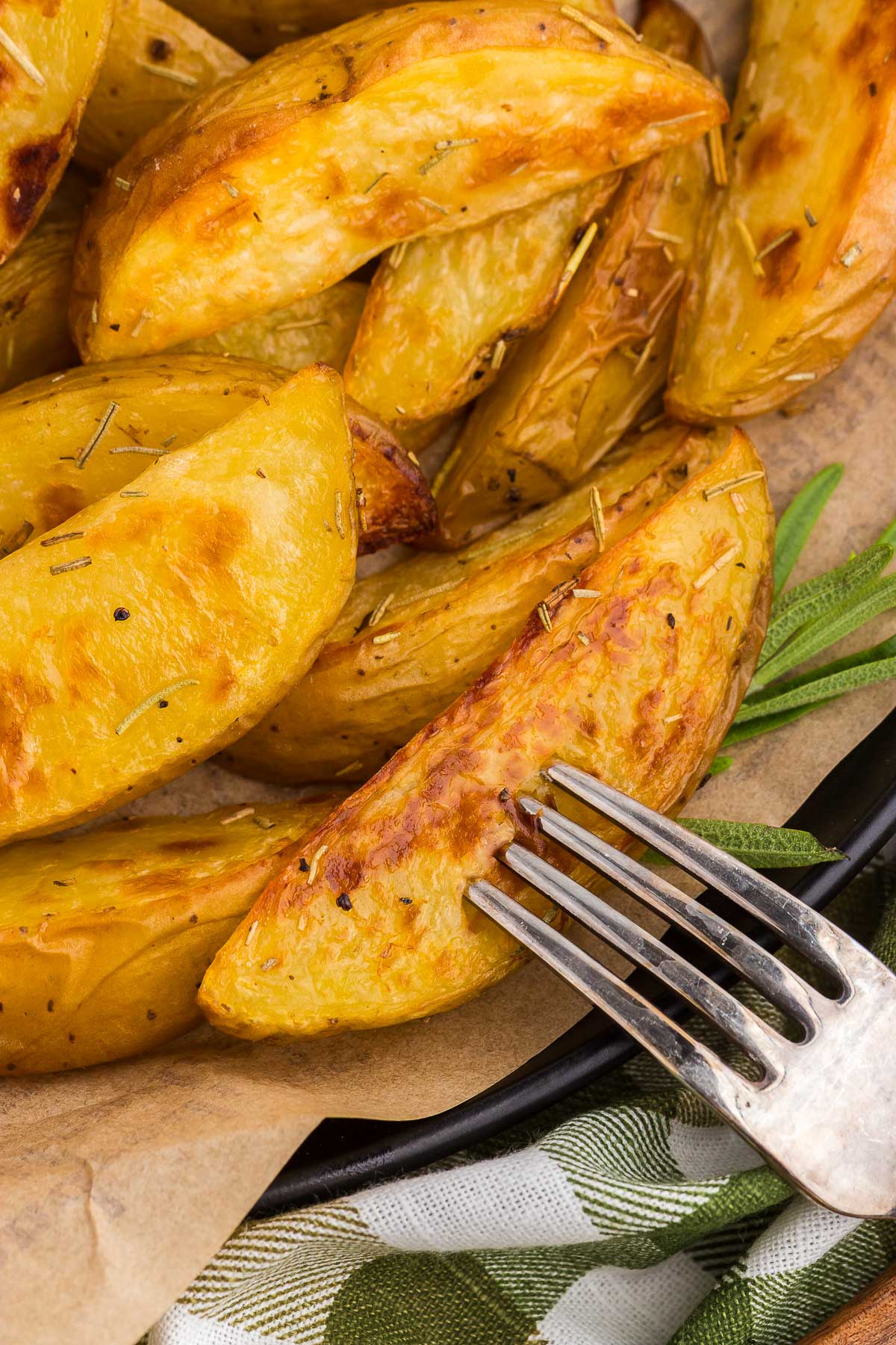 A fork stuck into a wedge of Rosemary Roasted Potatoes