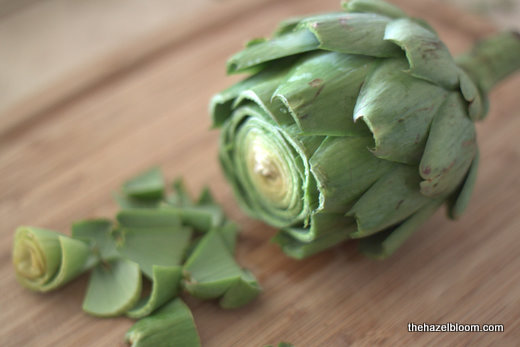 Lopping off the top of an artichoke in preparation for cooking
