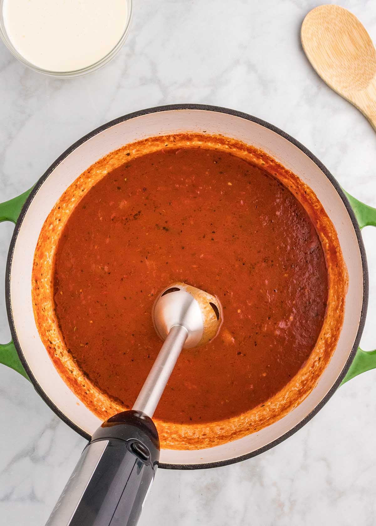 An immersion blender purees tomato soup into a creamy consistency.