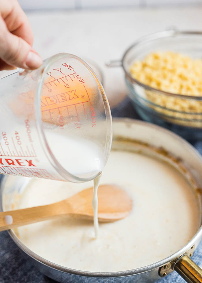 Pouring the milk into the pan for the best baked macaroni and cheese