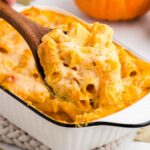 scooping out a spoonful of Creamy Baked Pumpkin Pasta with a wooden spoon