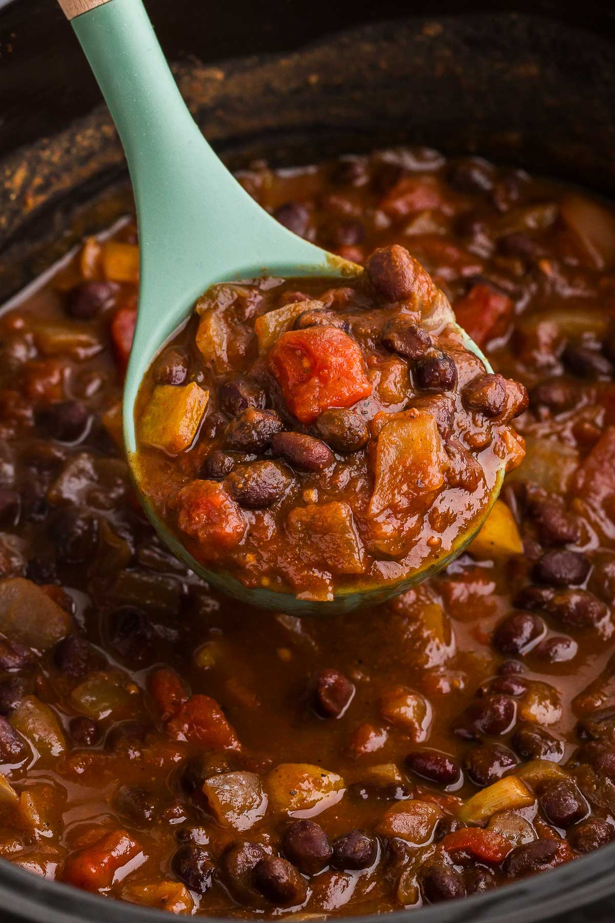 a scoop of pumpkin chili is scooped out of the Crockpot