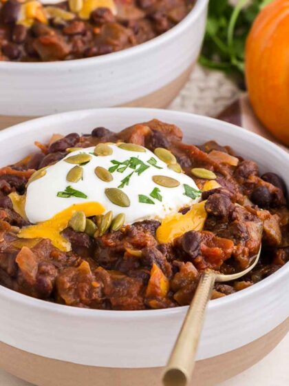 a bowl of pumpkin chili with a gold spoon in it