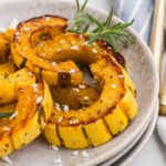close-up of roasted delicata squash with rosemary and feta on white plates
