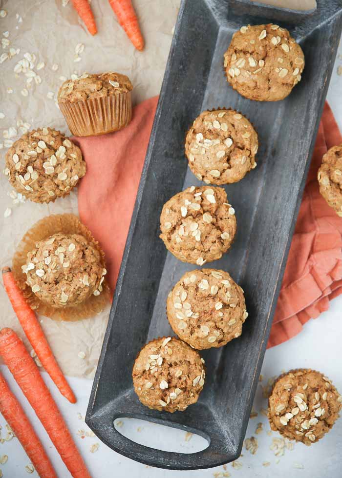 Carrot muffins lined up on a long tray, sprinkled with oats