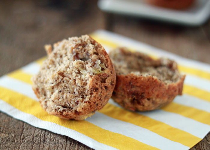 A vegan banana bread muffin, split in half, on a yellow and white napkin.