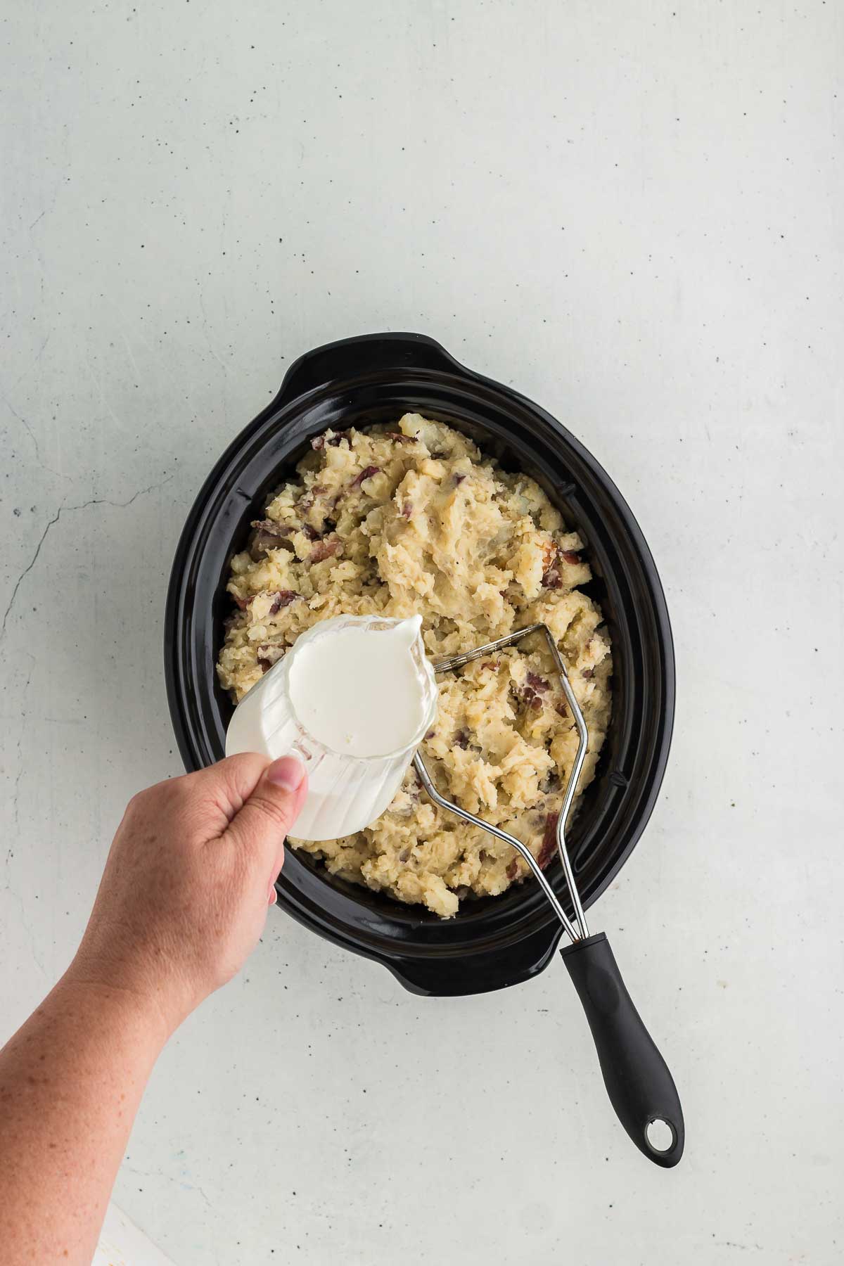 adding milk to Crock Pot Mashed Red Potatoes