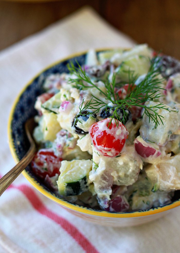 Creamy Greek Potato Salad recipe - Garlicky Greek yogurt tzatziki sauce forms the creamy base of this potato salad; a healthier, more protein-packed spin on the traditional mayo. Add kalamata olives, cherry tomatoes, red onions, and cucumber for fun and refreshing potato salad alternative. 