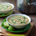 Two bowls of vegetarian chili verde on a wooden cutting board.