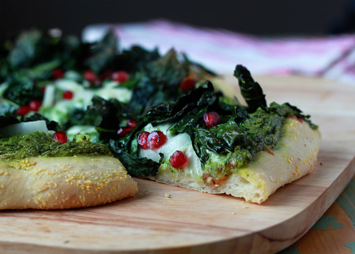 Kale & Pomegranate Pizza with Creamy Pesto Sauce recipe. Two doses of kale - both in the creamy, garlicky pesto and piled on top - make this vegetarian pizza a green powerhouse (in the most delicious way, promise!) Top with ruby-red pomegranate arils for color and a little irresistible sweet and salty contrast.