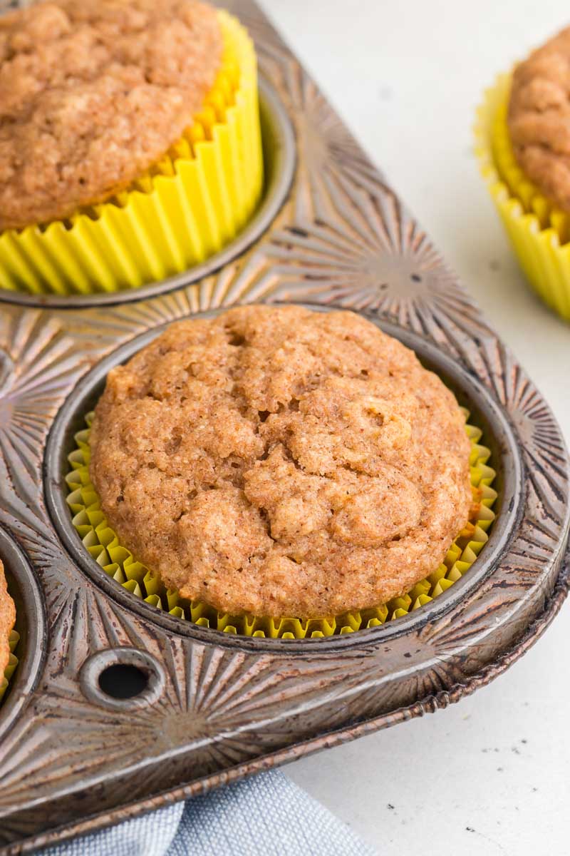 close up of a honey banana muffin in a vintage tin with a yellow wrapper