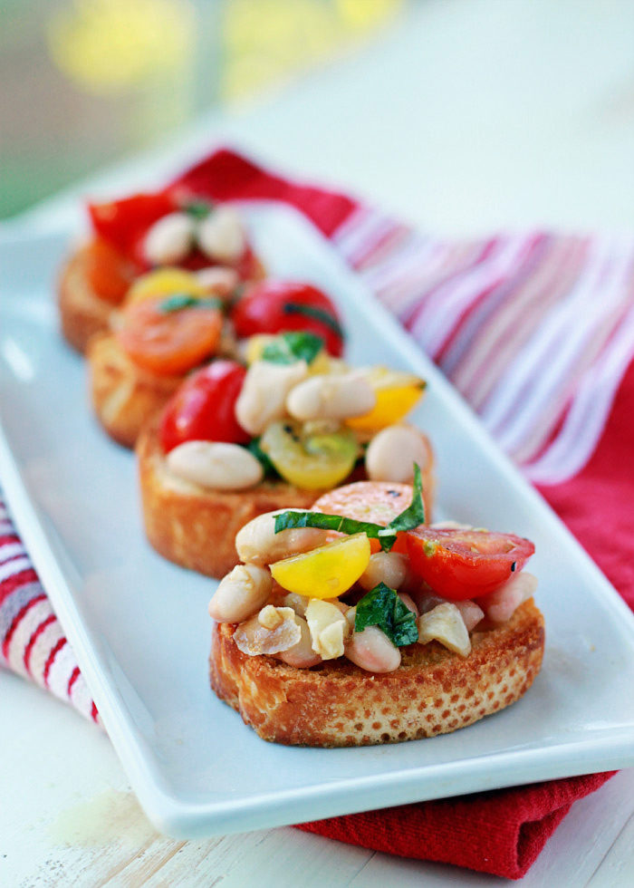 Cherry Tomato and White Bean Bruschetta - Fresh tomatoes and creamy white beans tossed with basil, balsamic, and loads of garlic, then loaded onto crunchy golden toasts. So pretty much the tastiest appetizer recipe in the history of the land. 