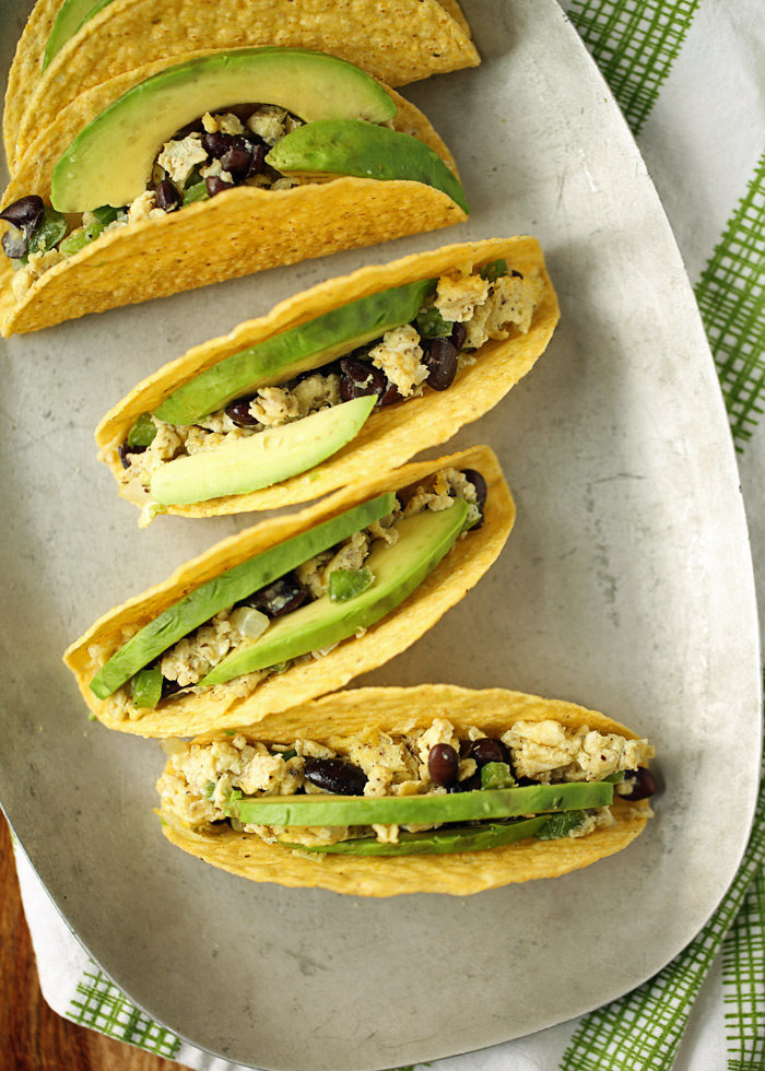 Scrambled eggs flecked with veggies and black beans, stuffed into a crunchy taco shell and topped with creamy avocado. These grab-and-go breakfast tacos are ready in 10 minutes flat! Gluten-free, dairy-free, and vegetarian (but with options for everyone!)