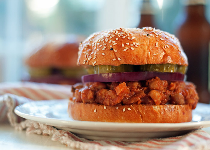 A bbq chickpea sloppy Joe on a plate with an orange and beige striped napkin. 