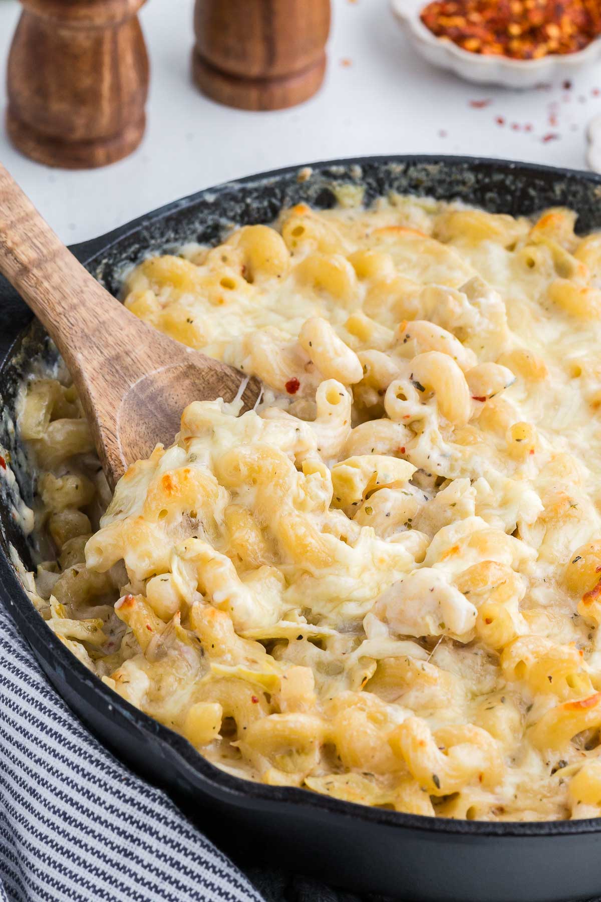 a skillet with creamy artichoke pasta with a wooden spoon