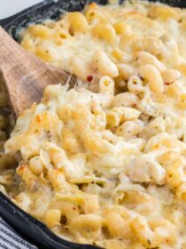 cream artichoke pasta bake in a skillet with a wooden spoon