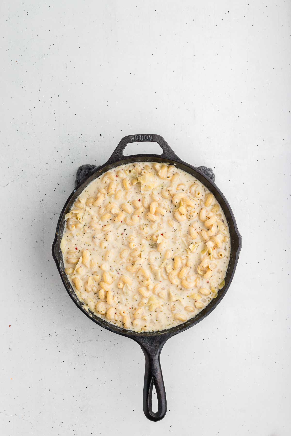 top view of skillet with ingredients for artichoke pasta bake