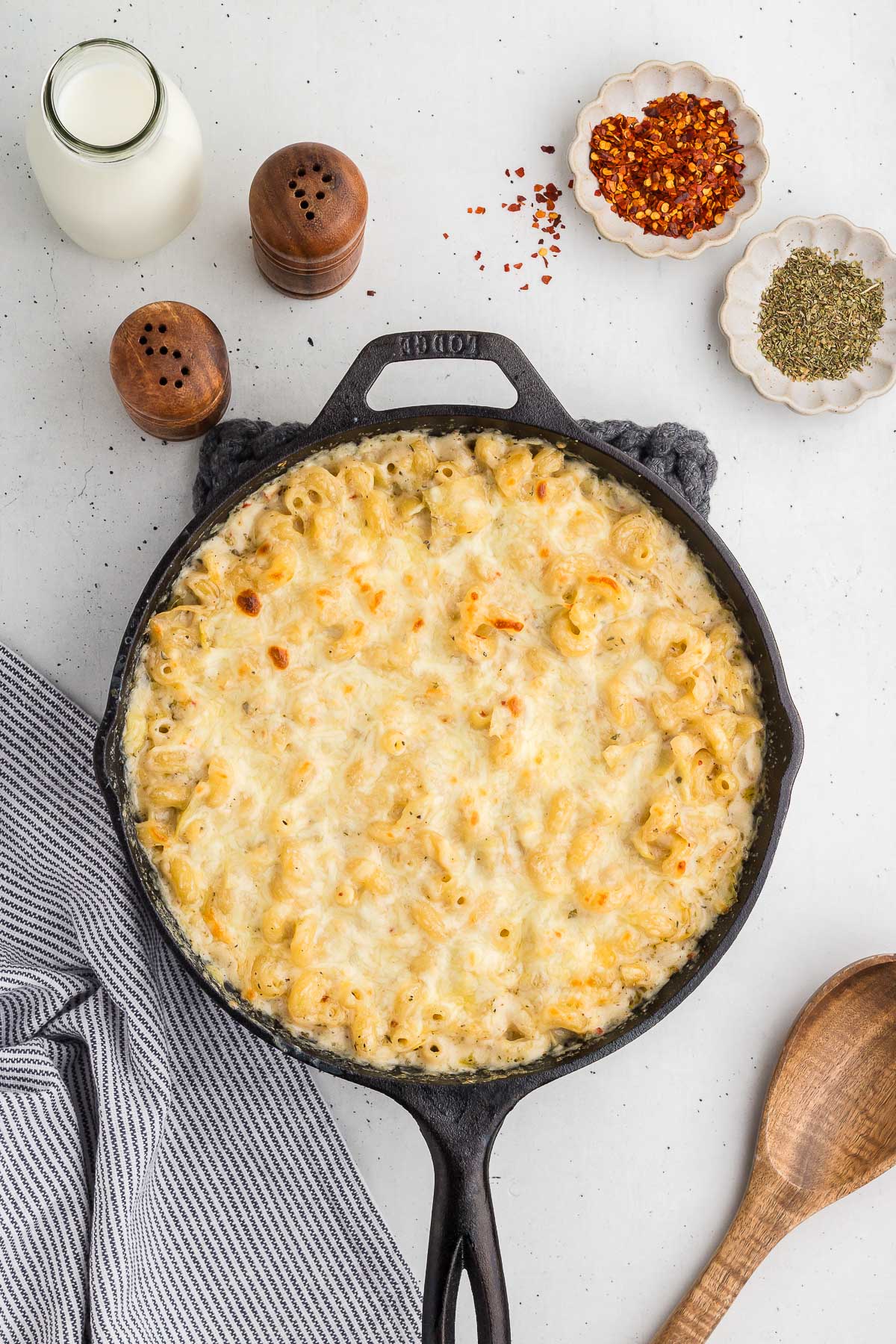 top view of baked artichoke pasta in a skillet with ingredients all around