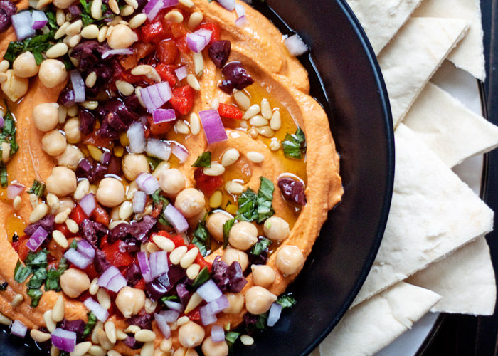 Loaded Roasted Red Pepper Hummus recipe - Smooth, full-of-flavor hummus smothered in Mediterranean toppers. Dip away!
