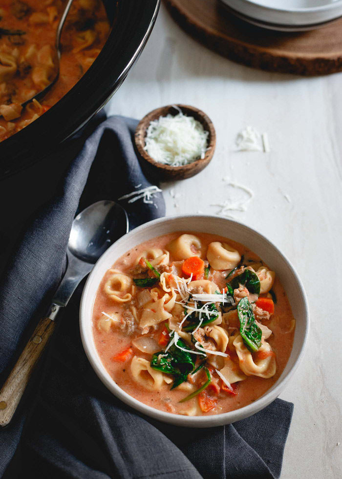 Slow Cooker Creamy Tortellini Spinach Soup recipe - Thick, rich, and hearty, this vegetarian soup is the perfect comforting end to a cool day. Tortellini, spinach, tomatoes, and cheese - what could go wrong?! Just add sausage for the meat-eaters.