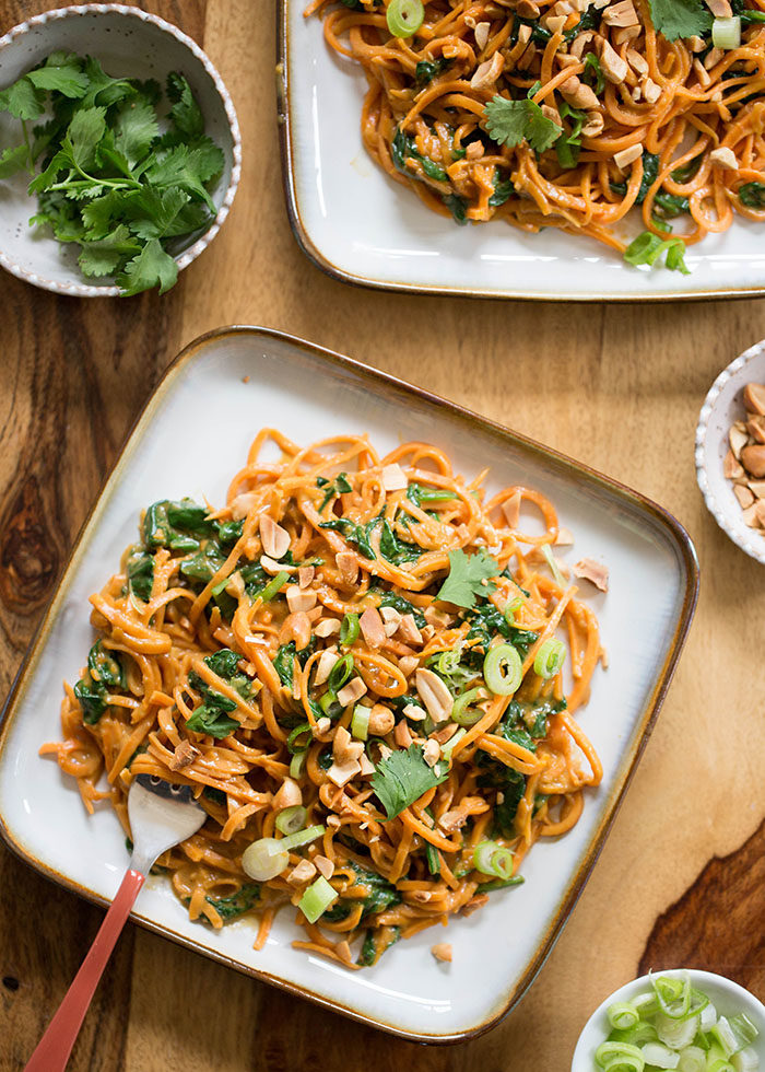 Spiralized sweet potatoes tossed with spinach, drenched in peanut sauce, and topped with crunchy peanuts. Increase the protein factor by topping with baked tofu or - if any carnivores are at your table - some grilled chicken. #vegan #onedishtwoways #sweetpotatonoodles