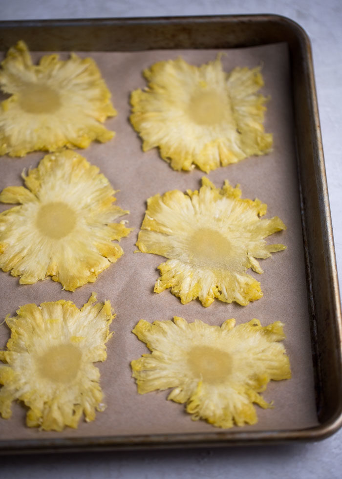 How to Make Dried Pineapple Flower Garnishes for cupcakes, cakes, cocktails and more. Paper-thin pineapple slices, oven-dried into yellow-flower perfection. Easy-to-follow, step-by-step instructions with photos showing exactly how to make these beauties. 