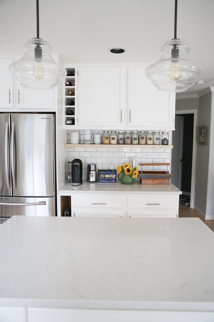 Budget-friendly white kitchen remodel. White quartz countertops, painted cabinets, whitewashed wood floors