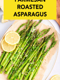 A top view of a white plate lined with parchment paper and parmesan roasted asparagus on top with lemon as garnish. The text reads, "parmesan roasted asparagus."