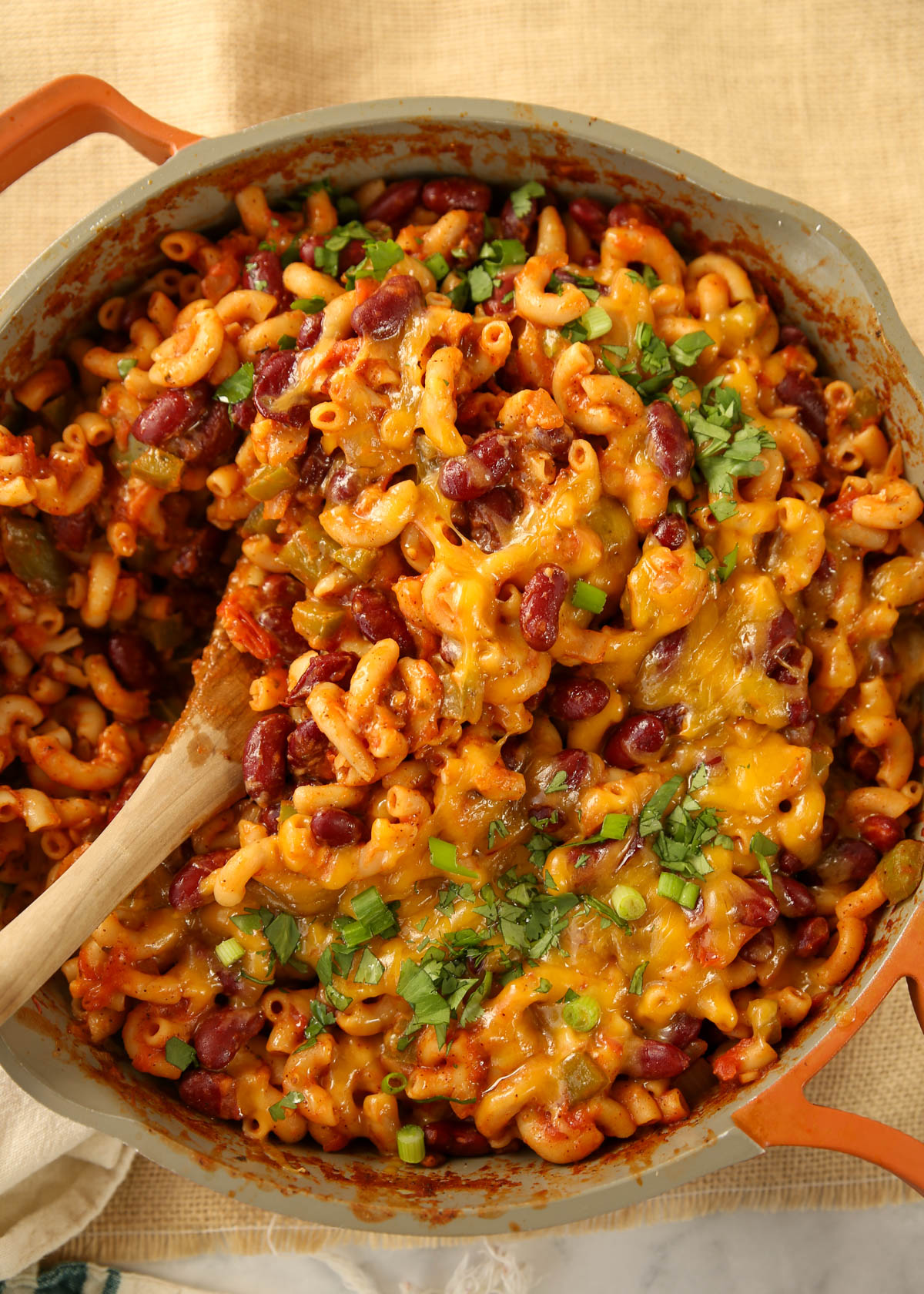 A top view of One-Pot Vegetarian Chili Mac in a pan with a wooden spoon.