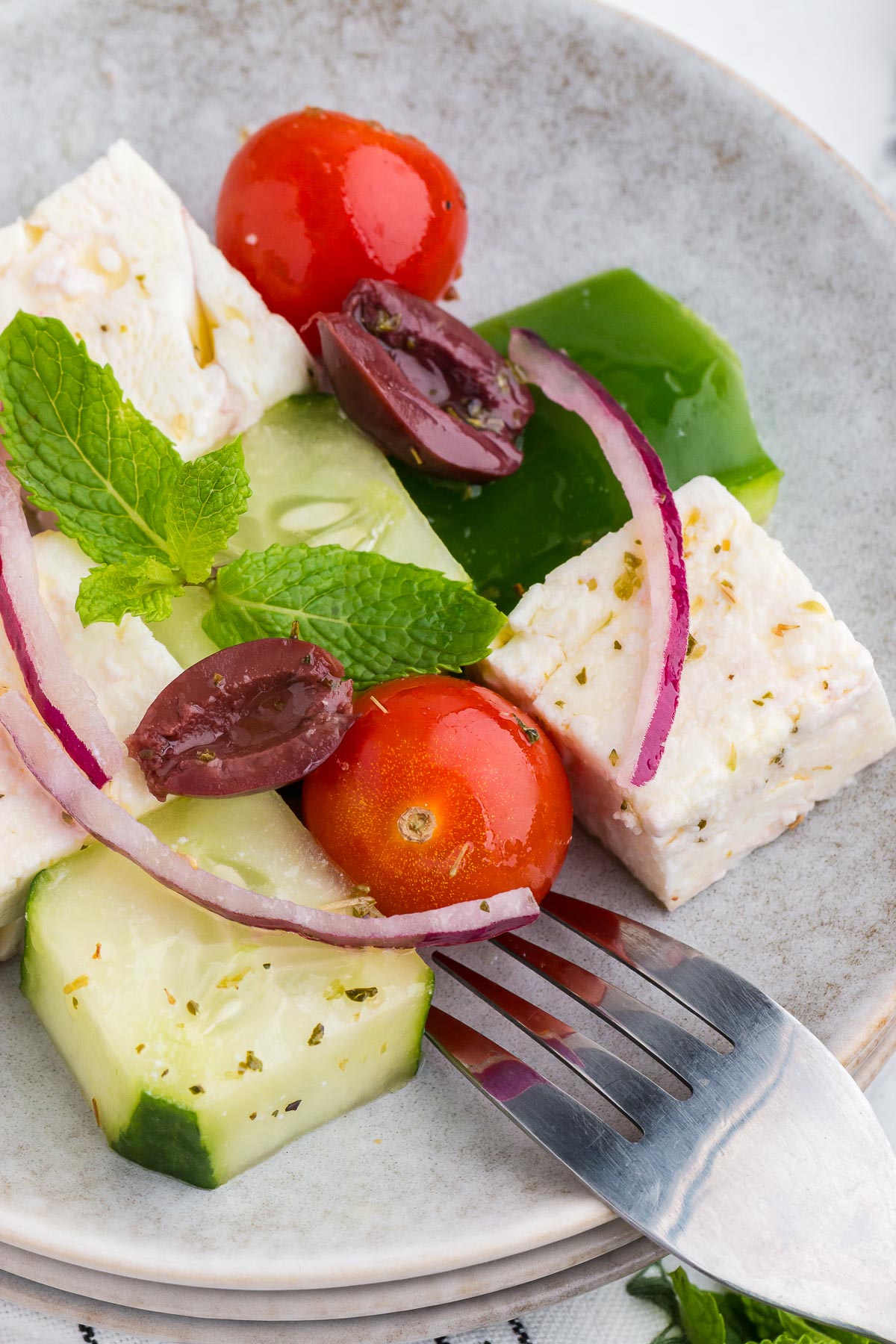Fourchette en argent avec assiette remplie de salade grecque en mosaïque