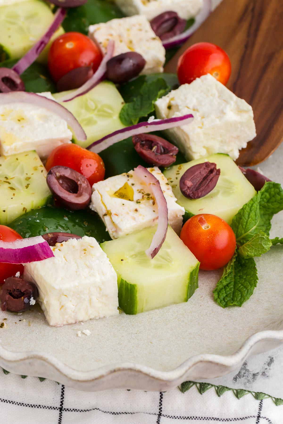 Gros plan de salade de mosaïque grecque sur une assiette blanche avec une cuillère en bois