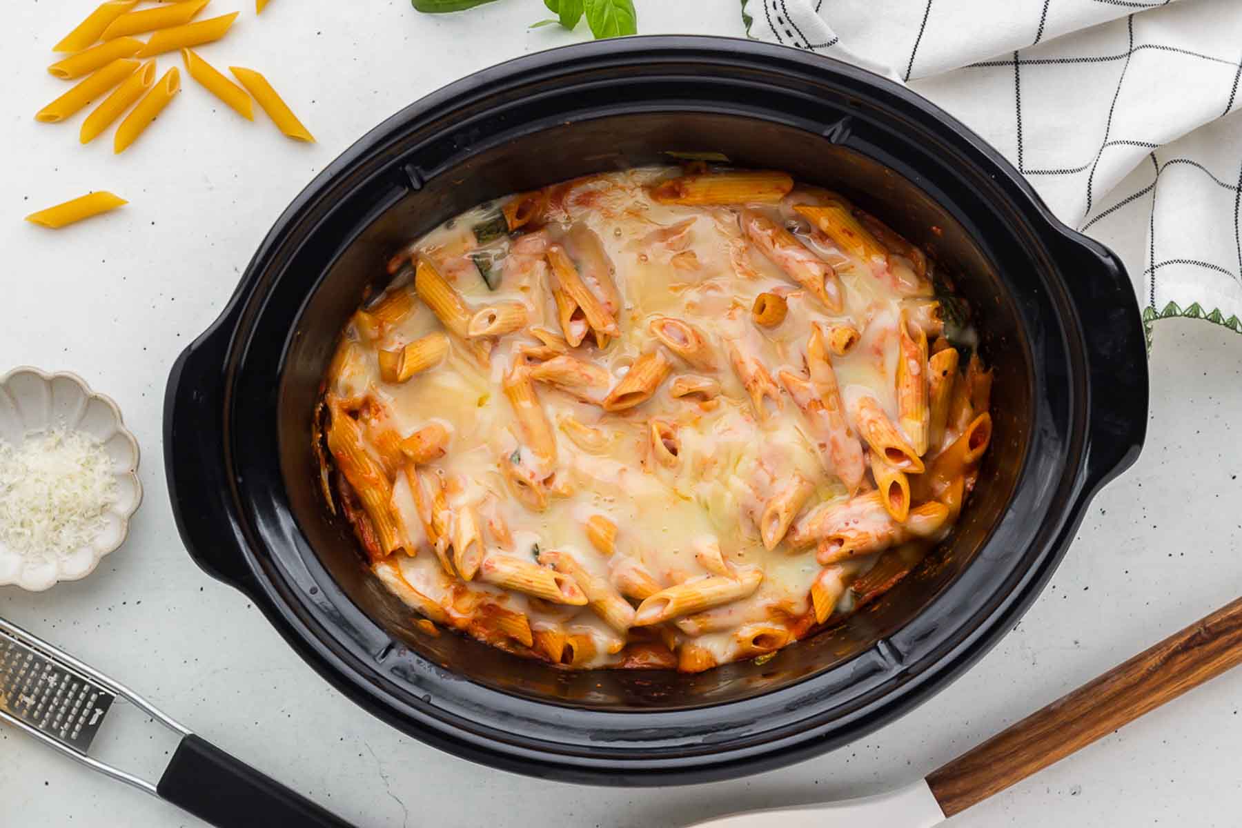 A black slow cooker full of cheesy Crock Pot Baked Ziti