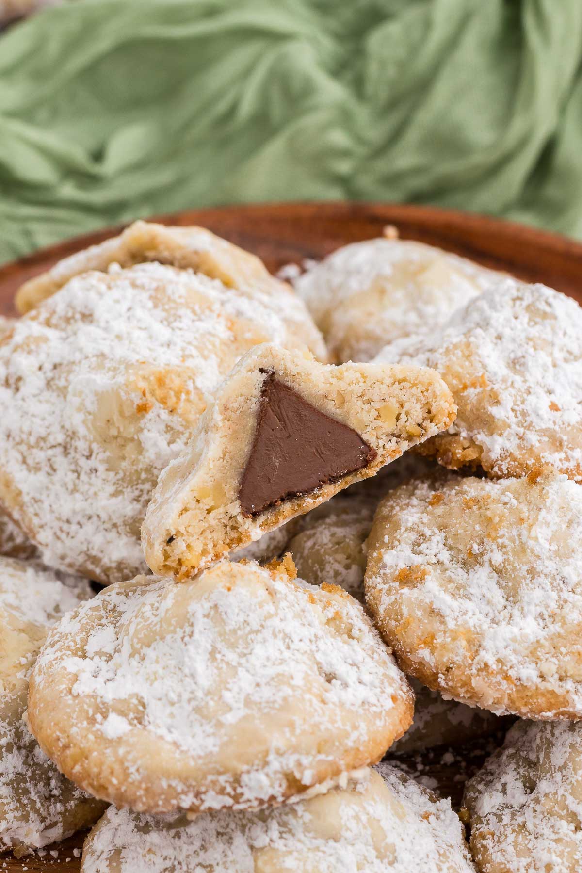 Plate of Hidden Kiss Cookies with one cut in half to show the center of the cookie with the Hershey's kiss inside
