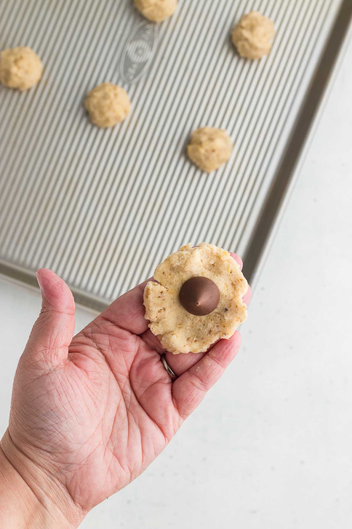 wrapping dough for Hidden Kiss Cookies around a Hershey's kiss