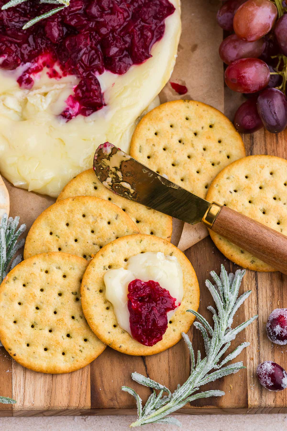 a cheese knife spreads cranberry baked brie on a cracker