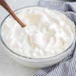 A glass mixing bowl full of freshly whipped cream