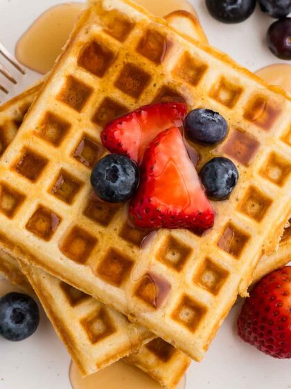 a top view of a stack of three waffles with syrup and berries