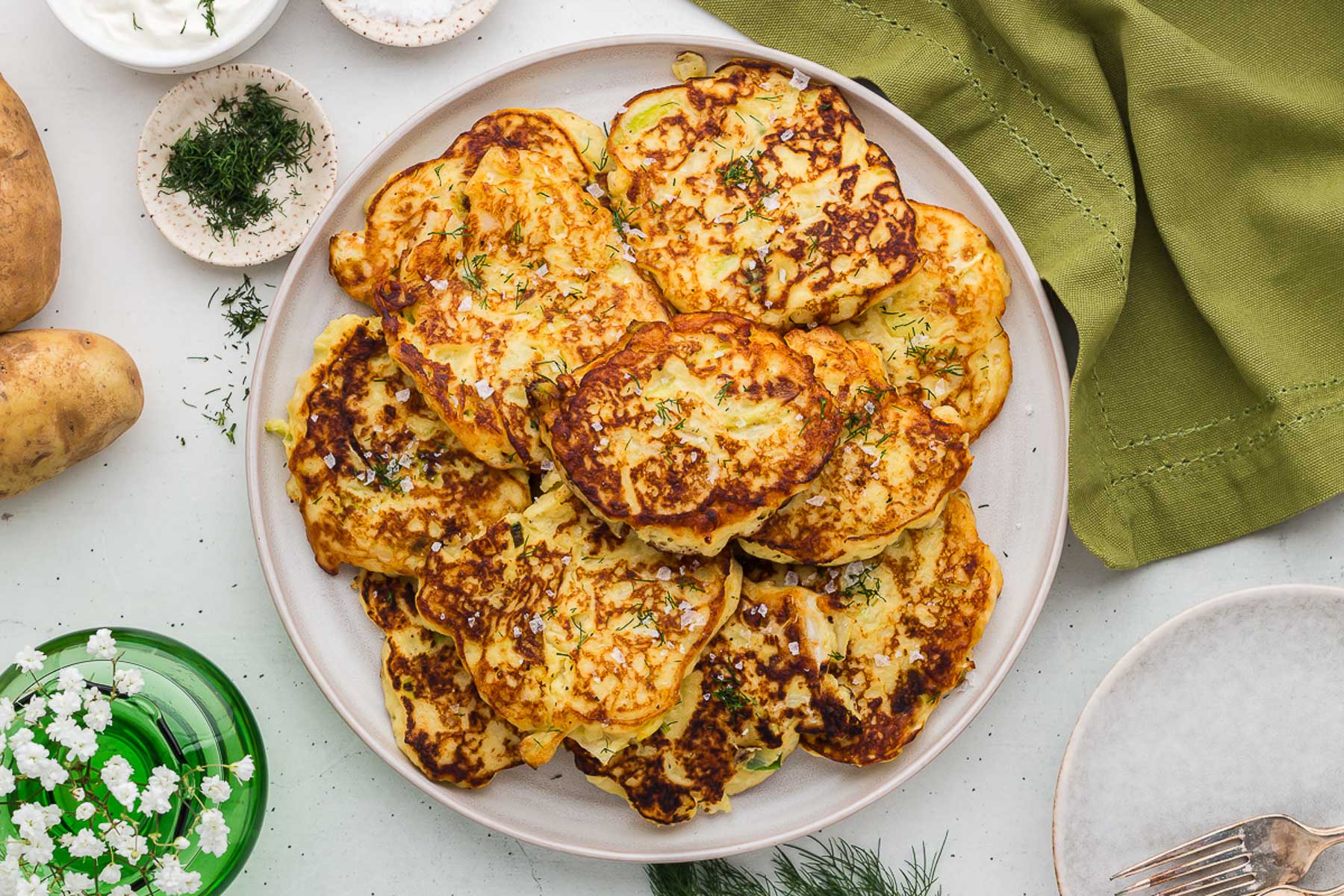 Plate full of colcannon cakes with flowers and dill in the background. 