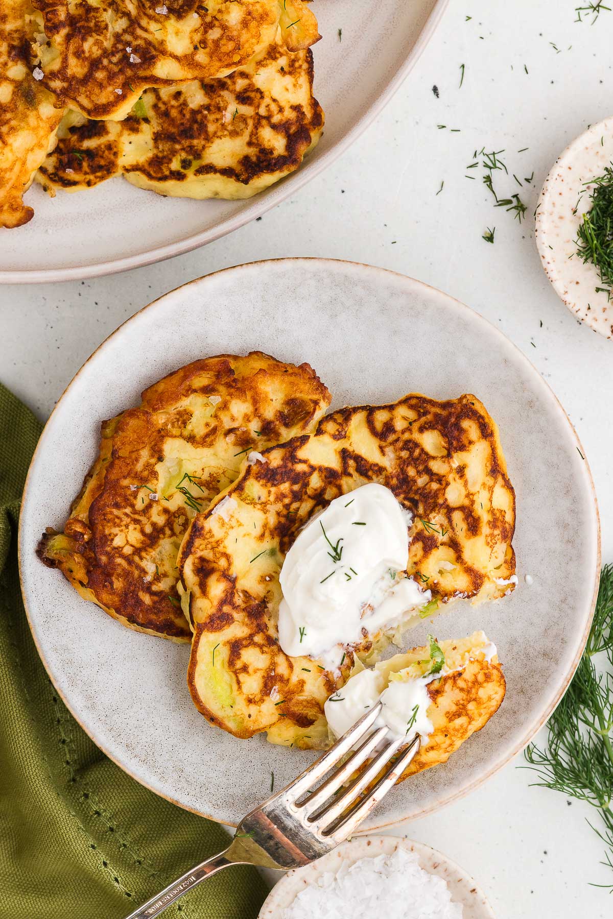 colcannon cakes on white stoneware plates with sour cream and dill