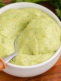 A wood and silver spoon scoops out a serving of Avocado Lime Crema