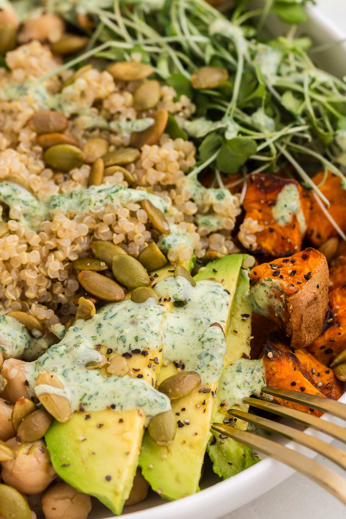 Grain bowl with green goddess sauce in a white bowl with a gold fork