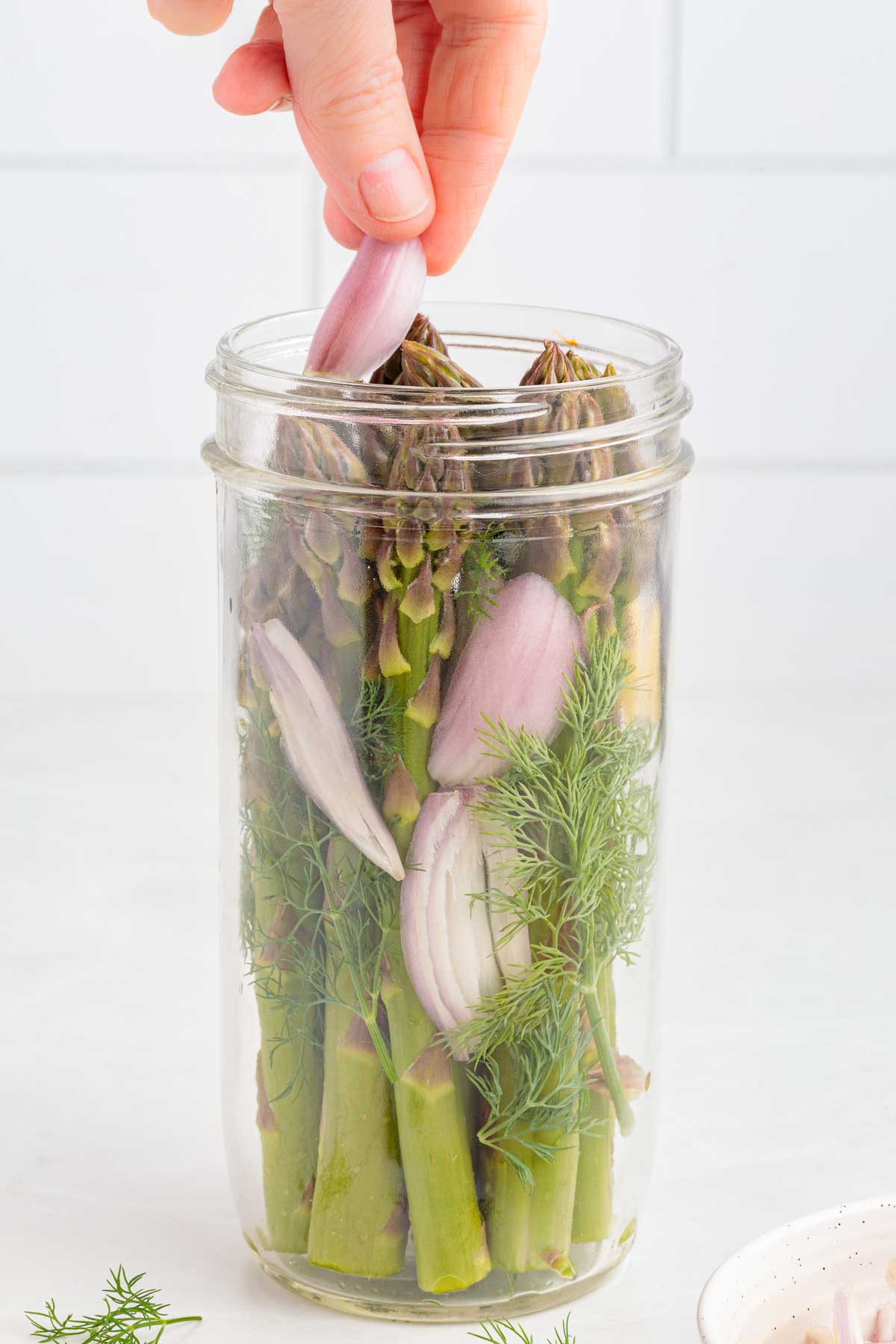 placing shallots in a jar of asparagus for quick-pickled asparagus
