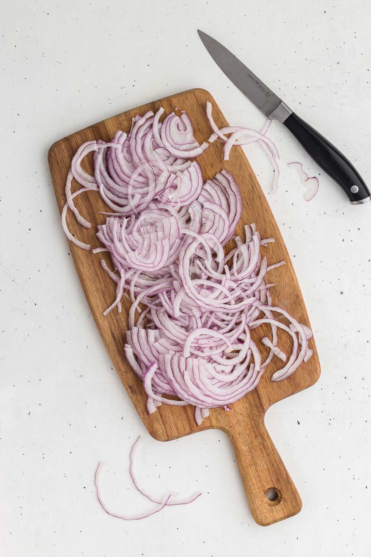 thinly sliced red onions on a cutting board for quick-pickled red onions