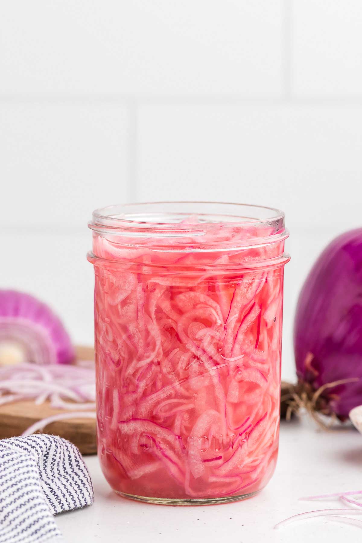 quick-pickled red onions in a mason jar with a white background
