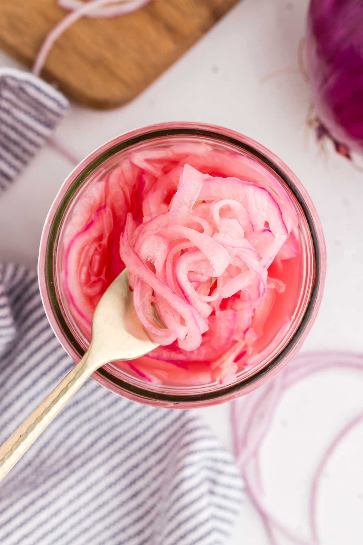 quick-pickled red onions being lifted out of a jar