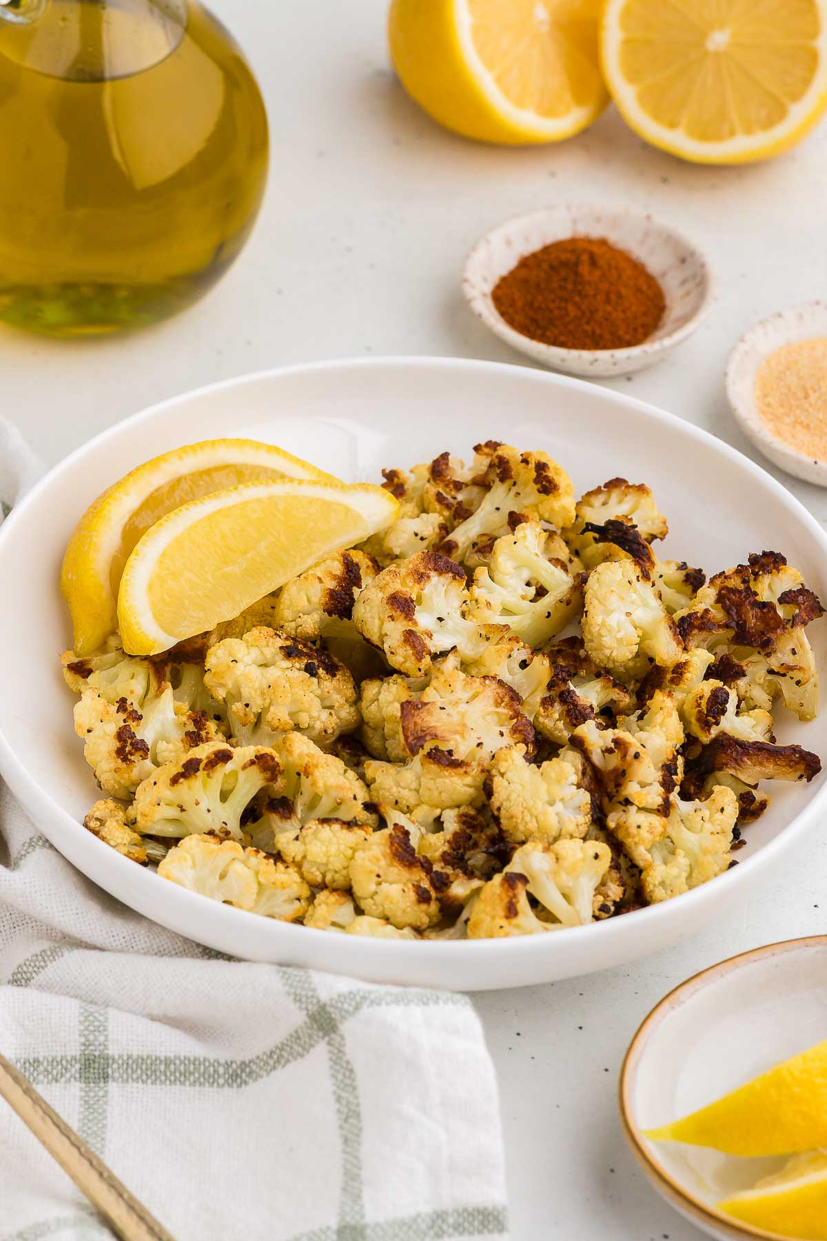 Roasted Cauliflower in a white bowl with lemons in the background