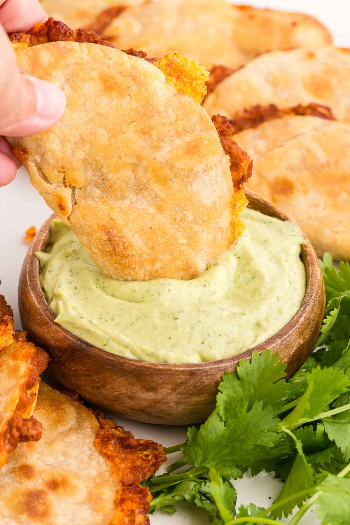 dipping a crispy baked taco in avocado crema